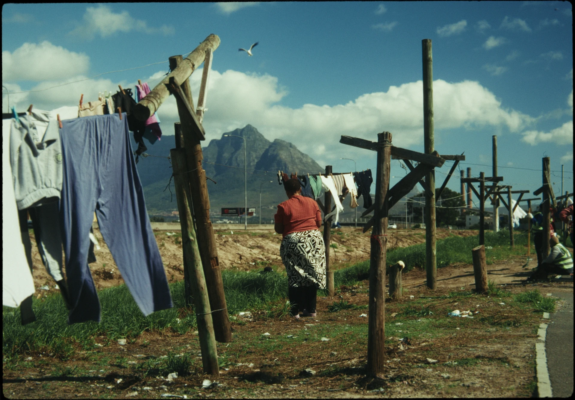 Une femme étend du linge au pied des montagnes.