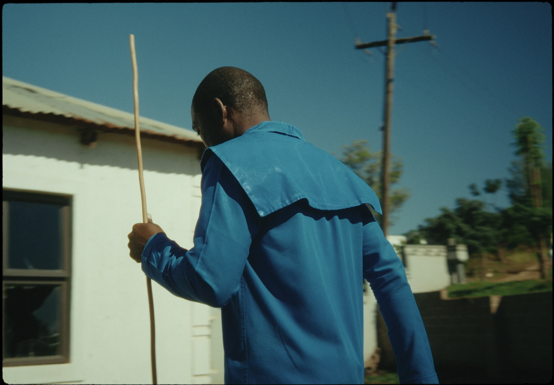 Un homme en tenue bleue marche avec un bâton.
