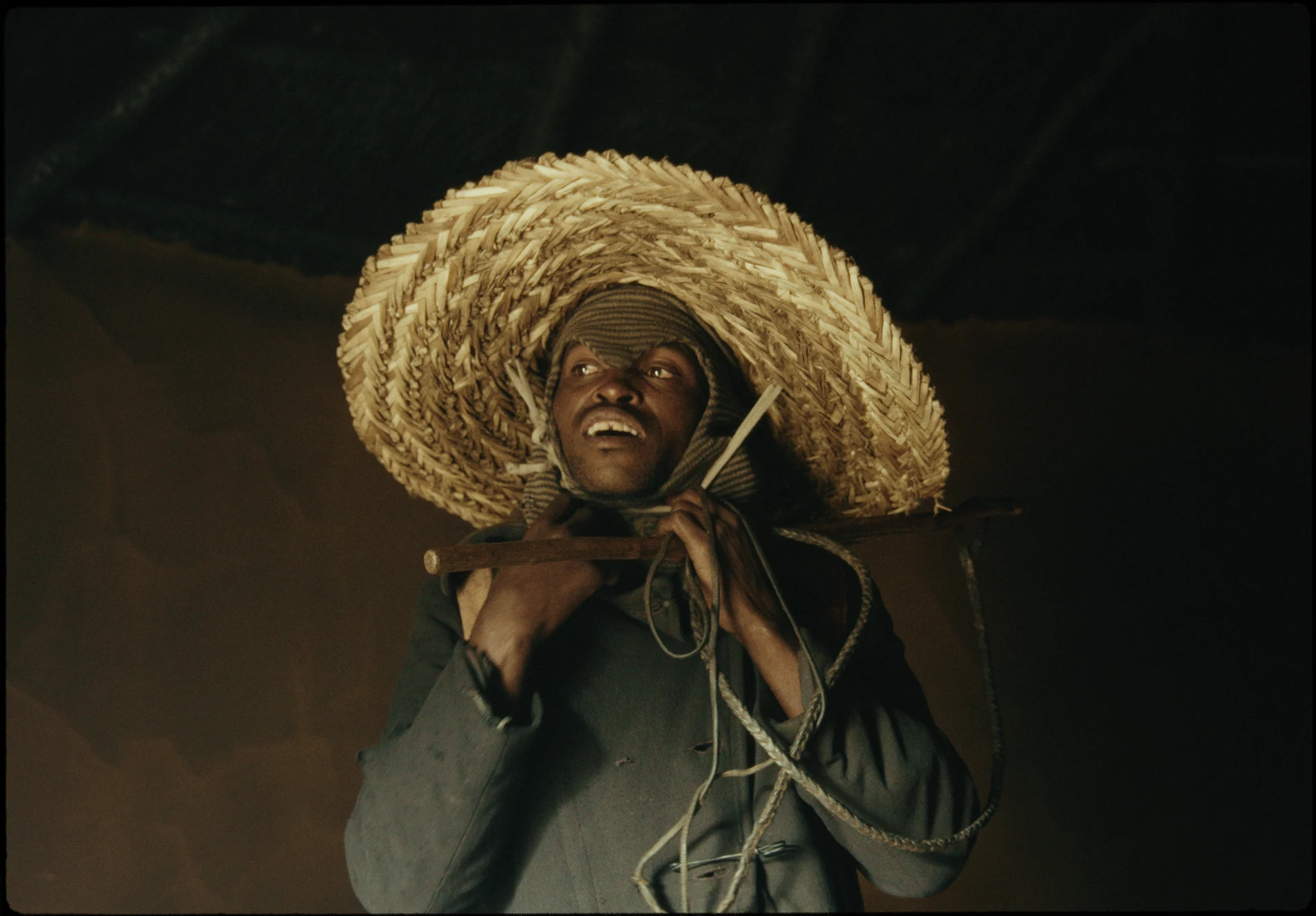 Un homme porte un grand panier de paille sur ses épaules.
